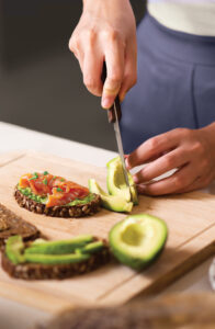 A person cutting an avocado on a cutting board
